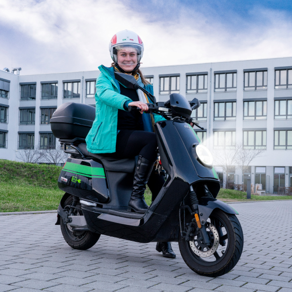Ronja auf einem Motorroller vor Robotrongebäude